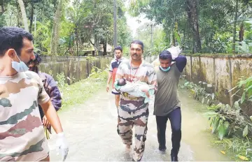  ?? — AFP photo ?? An Indian rescue worker carries a baby boy rescued with his family from homes in a water-logged area as they are moved to a relief camp in Chenagannu­r.