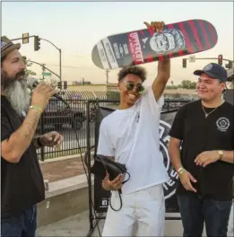  ??  ?? Eternal Ministries co-founder Albert Zavala (left) presents El Centro’s Ambrose Dawson (center) with a new skateboard Thursday. PHOTO CRIS LOPEZ