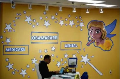  ?? REBECCA BLACKWELL/ASSOCIATED PRESS ?? An employee worked beside decoration­s depicting Odalys Arevalo as a fairy godmother, at Las Madrinas de los Seguros (Spanish for “The Godmothers of Insurance”).