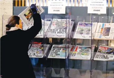  ?? Associated Press ?? A customer takes a copy of a newspaper tuesday headlining Prince Harry and Meghan’s explosive TV interview at a newspaper stand outside a shop in London. Britain’s royal family is absorbing the tremors from a sensationa­l television interview by Prince Harry and the Duchess of Sussex, in which the couple said they encountere­d racist attitudes and a lack of support that drove Meghan to thoughts of suicide.