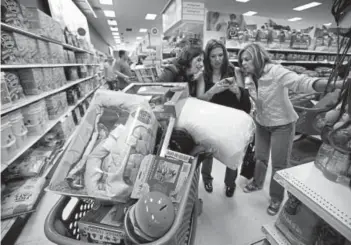  ?? Associated Press file ?? Target shoppers, from left, Kelly Foley, Debbie Winslow and Ann Rich use a smartphone to look at a competitor’s prices while shopping after midnight on Black Friday in 2014, in South Portland, Maine.