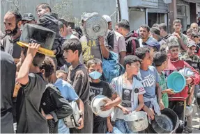  ?? AFP VIA GETTY IMAGES ?? Men and children line up to receive food rations from a public kitchen in Deir el-Balah in the central Gaza Strip on Monday.