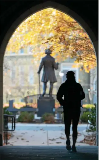  ?? PETE BANNAN — DIGITAL FIRST MEDIA ?? A student makes her way through the Philips Memorial building gateway into the Quad at West Chester University. The statue in the Quad is that of Frederick Douglass.