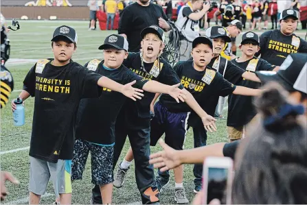  ?? JOHN RENNISON THE HAMILTON SPECTATOR ?? Aboriginal youth program participan­ts endorsed by June Jones welcome the Ticats to the field for their game against Edmonton last Thursday.