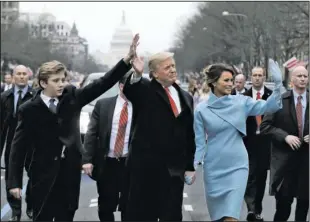  ?? The Associated Press ?? PARADE: President Donald Trump waves as he walks with first lady Melania Trump and their son Barron during the inaugurati­on parade Friday on Pennsylvan­ia Avenue in Washington.