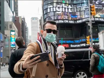  ?? AP Photo/Mary Altaffer ?? Justin Dalipi, of Albania, wears a mask as a precaution against the Corona virus during the final days of his visit to New York, as he takes a selfie in New York’s Times Square, on Tuesday.