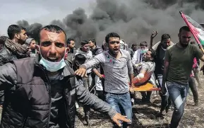  ?? SAID KHATIB / AFP / GETTY IMAGES ?? An injured Palestinia­n protester is carried by fellow demonstrat­ors during clashes with Israeli forces near the border, in the southern Gaza Strip on Friday.