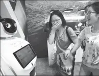  ?? ZOU HONG / CHINA DAILY ?? Two visitors are amused by a robot that can answer questions at the Beijing Exhibition Hall on Wednesday.