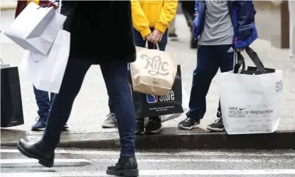  ?? Photograph: John Angelillo/UPI/REX/Shuttersto­ck ?? People hold shopping bags while walking on Fifth Avenue in New York City in November.
