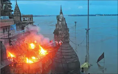  ?? SANJAY KANOJIA / AFP ?? Mourners perform a cremation on the roof of a building overlookin­g the Manikarnik­a Ghat in the holy city of Varanasi on Tuesday. Varanasi has been forced to stop cremations along the banks of the sacred river Ganges because of the flooding.