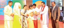  ??  ?? Prime Minister Mahinda Rajapaksa hands over a clay savings till to a child