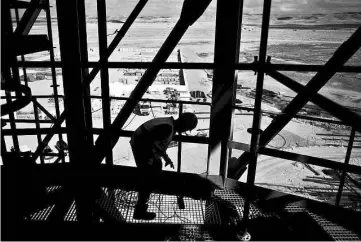  ?? — Reuters photos ?? A worker is silhoutted as he works on the constructi­on of a boiler at the building site of a 240 metre (787 feet) solar-power tower in Israel’s southern Negev Desert on Feb 8.The world’s tallest solar-power tower is being built off a highway in the...