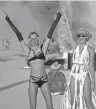  ??  ?? Models Ludi Delfino and Abby Neff pose for photos in front of a burning piece of artwork at Burning Man in 2018.