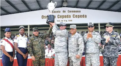  ??  ?? El mayor general Luís Napoleón Payán Díaz, comandante de la Fuerza Aérea de República Dominicana, levanta la copa de campeón tras recibirla de manos del teniente general Rubén Paulino Sem, ministro de Defensa, y del vicealmira­nte Juan Ramón Soto de la...