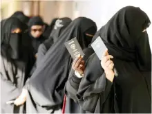  ??  ?? KUWAIT: Kuwaiti women show their passports as they arrive at a polling station to cast their votes for the parliament­ary elections yesterday.