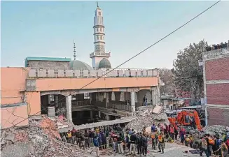  ?? Abdul Majeed / AFP/Getty Images ?? Security personnel and rescue workers prepare to search for the blast victims in the debris of a damaged mosque inside the police headquarte­rs in Peshawar on Monday.