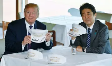  ?? (Reuters) ?? US PRESIDENT Donald Trump and Japanese Prime Minister Shinzo Abe pose after they signed hats reading ‘Donald and Shinzo, Make Alliance Even Greater,’ at a country club near Tokyo yesterday.