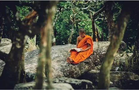  ??  ?? CALM CORNER: A Cambodian Buddhist reads a book under a tree near a temple on a hill in Bokor National Park in Cambodia. TOP RIGHT: Buildings along a river in Kampot. ABOVE RIGHT: An abandoned temple in Phnom Bokor, Kampot Province.