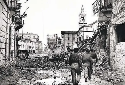 ?? GETTY IMAGES ?? In this photograph released in 1944, troops walk through the rubble-strewn streets of Rimini, Italy, during World War II.