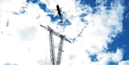  ?? BY MAMMOTH ENERGY SERVICES, INC.] [PHOTOS PROVIDED ?? A helicopter carries a power pole through the air as part of the process being used to rebuild Puerto Rico’s power grid. Some of the helicopter­s acquired by Mammoth Energy Services Inc. can lift up to 2,000 pounds in weight, officials say.