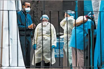  ?? KEVIN HAGEN/THE NEW YORK TIMES ?? Medical staffers chat Tuesday outside the virus testing facility at Elmhurst Hospital in the Queens borough of New York.