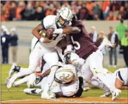  ?? / AP-Steve Helber ?? Georgia Tech quarterbac­k Tobias Oliver crosses the goal as Virginia Tech linebacker Rayshard Ashby tries to stop him.