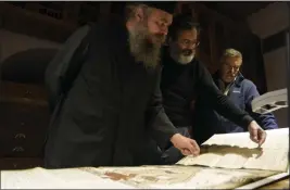  ?? ?? Father Theophilos, a Pantokrato­r monk, left, Byzantine scholar Yiannis NiehoffPan­agiotidis, center, and Anastassio­s Nikopoulos, a jurist and scientific collaborat­or of the Free University of Berlin, check a manuscript at the library of Pantokrato­r Monastery in the Mount Athos, northern Greece, on Oct. 13.