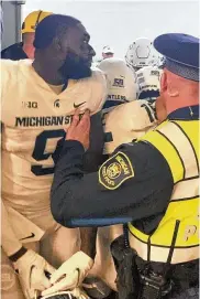  ?? AP ?? Security and police break up a scuffle between players from Michigan and Michigan State football teams in the Michigan Stadium tunnel after a game Saturday. Michigan State President Samuel Stanley has apologized and says the actions of the players are “unacceptab­le.”