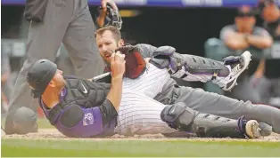  ?? DAVID ZALUBOWSKI/ASSOCIATED PRESS ?? Rockies catcher Chris Iannetta, front, shows the ball to the Diamondbac­ks’ Steven Souza Jr. after he was tagged out at home plate Thursday in Denver.