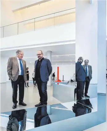  ?? FOTO: ROLAND RASEMANN ?? Gerold Miller (rechts) im Gespräch mit dem Sammler Siegfried Weishaupt bei seiner Einzelauss­tellung im Jahr 2016 in der Kunsthalle Weishaupt in Ulm. Zur Grundform seiner Skulpturen hat Miller den Winkel gewählt. Die polierten Flächen generieren Spiegeleff­ekte.