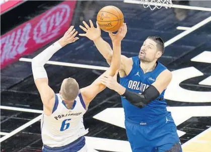  ?? JOHN RAOUX/AP ?? Magic center Nikola Vucevic fouls Dallas center Kristaps Porzingis (6) as he tries to block his shot during the second half on Monday night at Amway Center.