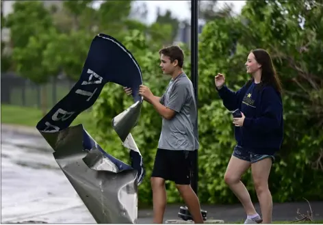  ?? PHOTOS BY ANDY CROSS — THE DENVER POST ?? Evan Schrader, left, 14, and his sister, Emily, 17, look over a piece of a scoreboard from Valor Christian High School that landed into the Camden Highlands Ridge parking lot from a tornado in Highlands Ranch on Thursday.