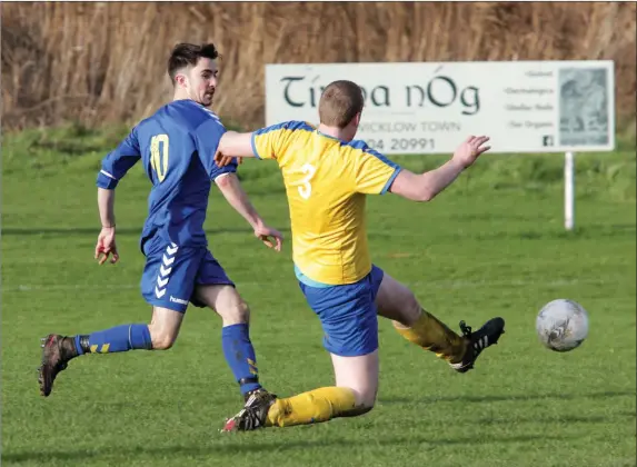  ??  ?? Gareth Murphy of Wicklow Town slides the ball to the net as John Condren of Seaview Wanderers attempts to get a block in.