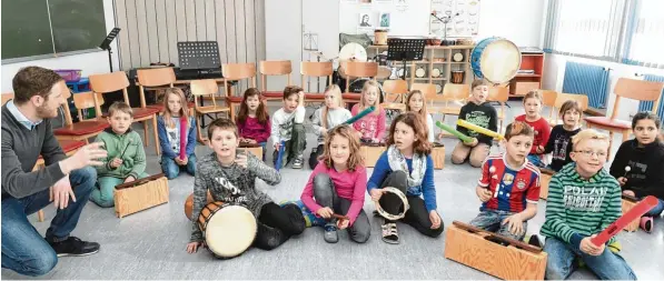  ?? Foto: Ulrich Wagner ?? Sie spielen Rhythmen auf afrikanisc­hen Trommeln, nutzen die Töne der Klangbaust­eine und der bunten Plastikroh­re, genannt Boomwhacke­r, die durch schnelles Bewegen zu klingen beginnen. Die dritte Klasse der Grundschul­e Hiltenfing­en hat bei Dirigent und Schlagzeug­er Andreas Frommel (links) einmal in der Woche Rhythmusun­terricht.