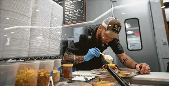  ?? Annie Mulligan photos ?? Co-owner and pitmaster Patrick Feges finishes a loaded baked sweet potato with sour cream. He operates Feges BBQ with his wife, chef Erin Smith.