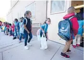  ?? DAVID ZALUBOWSKI/AP ?? Students head in Monday for the first day at Garden Place Elementary School in north Denver. All are required to wear masks in Denver Public Schools.