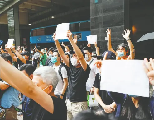  ?? Tyrone Siu/ REUTERS ?? Supporters raise sheets of blank white paper Friday to avoid slogans banned under the national security law as they support an arrested anti-law protester in Hong Kong.