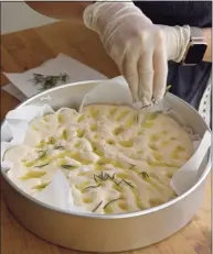  ?? H John Voorhees III / Hearst Connecticu­t Media ?? Barbara Nicolini, of Brookfield, sprinkles rosemary on a focaccia bread she is preparing for the oven.