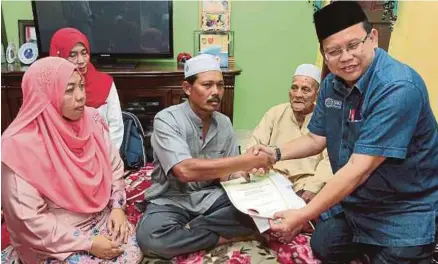  ?? [FOTO SYAMSI SUHAIMI/BH] ?? Abdul Ghaffar (kanan) menyerahka­n sijil pelepasan hutang PTPTN dan Manfaat Takaful kepada Ibrahim di Alor Pasir, Pasir Mas, semalam.