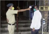  ??  ?? A BMC guard checks the temperatur­e of an employee as he enters the BMC Headquarte­rs on Thursday.