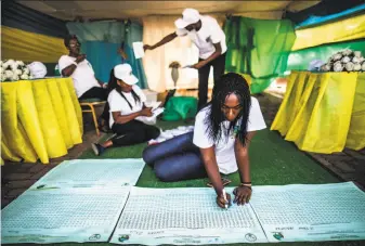  ?? Marco Longari / AFP / Getty Images ?? Election officials use a counting board at a polling station in Kigali. Paul Kagame is expected to win a third term at the helm of the nation that he has ruled with an iron fist for 23 years.
