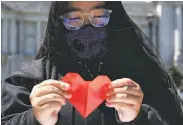  ??  ?? Jordyn Owyoung holds an origami heart during a unity event against antiAsian violence at Civic Center Plaza, as part of the Campaign for Solidarity.