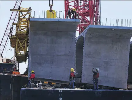  ?? ALLISON HESS / THE VIRGINIAN-PILOT VIA AP ?? Constructi­on staff work on the new Bonner Bridge along the Oregon Inlet in North Carolina. Canada’s top civil servants are worried that ambitious infrastruc­ture plans in the U.S. could push up constructi­on costs in Canada, according to documents.