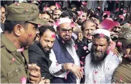  ?? AP ?? In this Thursday, October 19, 2017 file photo, supporters of Hafiz Saeed (centre), head of the Pakistani religious party, Jamaat-ud-Dawa, is showered with rose petals by his supporters as he arrives to a court in Lahore, Pakistan.