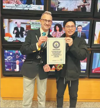  ?? PROVIDED TO CHINA DAILY ?? Wu Wuqiang displays his certificat­e from Guinness World Records for trapping the most glass bottles with a slinky in one minute in Milan, Italy, last year.