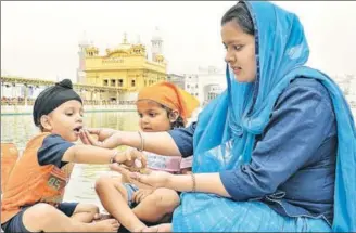  ?? PHOTOS: SAMEER SEHGAL ?? MORE THE MERRIER: Children are closest to God. No wonder young devotees are big fans of karah parshad. A family partaking of its share of the offering at the Golden Temple in Amritsar.