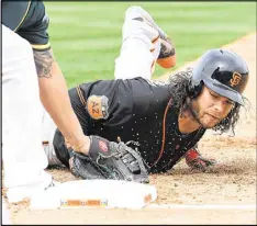  ??  ?? The Giants’ Brandon Crawford is picked off first base by A’s pitcher Kendall Graveman in the second inning Friday in Mesa, Ariz. Oakland won 6-1.