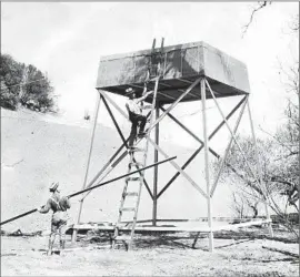  ??  ?? CHARLES HATFIELD (on ladder) and his brother built a tower east of San Diego in hopes of “wringing moisture from the air.” What followed was f looding.