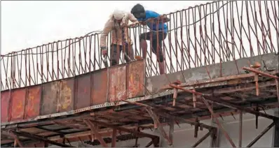  ?? (AFP) ?? Labourers work at the side of an under constructi­on flyover in New Delhi on Friday.