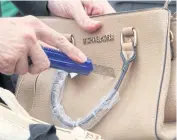  ?? APICHART JINAKUL ?? An official, in this filed photo, cuts a handbag with fake brand name during an event to destroy counterfei­t and pirate goods held by the Intellectu­al Property Department and police.